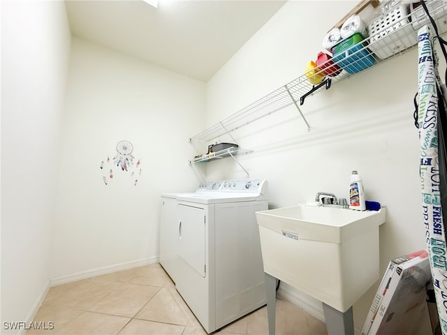 laundry room featuring laundry area, light tile patterned floors, baseboards, washing machine and dryer, and a sink