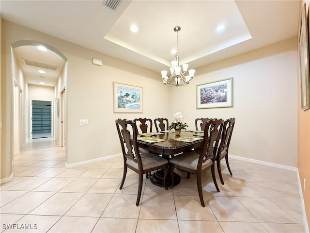 dining area with light tile patterned floors, a tray ceiling, visible vents, and a notable chandelier