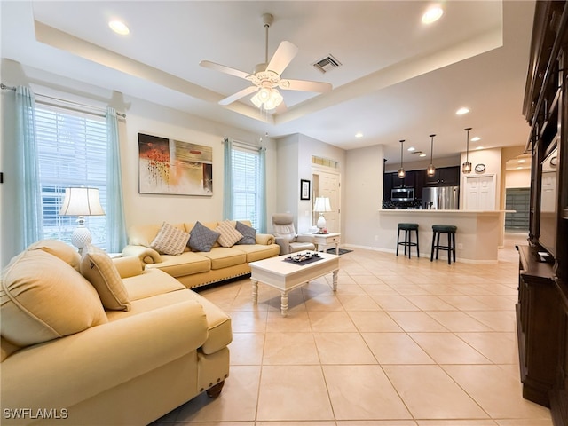 living room featuring light tile patterned floors, a tray ceiling, visible vents, and recessed lighting