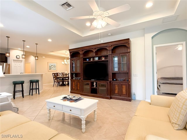 living room featuring a tray ceiling, light tile patterned flooring, visible vents, and recessed lighting