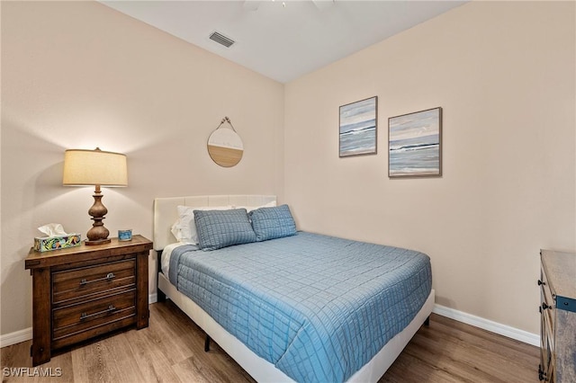 bedroom with baseboards, visible vents, and wood finished floors