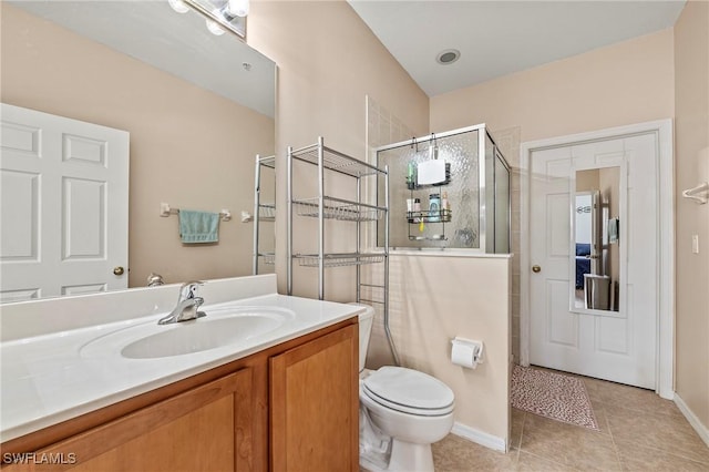 bathroom featuring toilet, a stall shower, vanity, tile patterned flooring, and baseboards