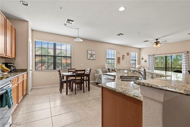 3791 Pino Vista Way Unit 201, Estero, FL 33928 - kitchen with a sink, brown cabinetry, light tile patterned floors, ceiling fan, and baseboards