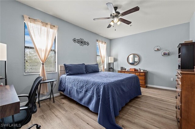 bedroom featuring a ceiling fan, light wood-style flooring, and baseboards