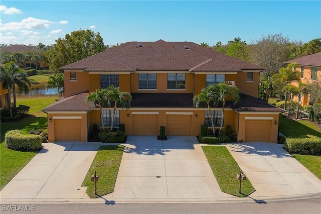 view of front of property with a front yard, concrete driveway, an attached garage, and stucco siding