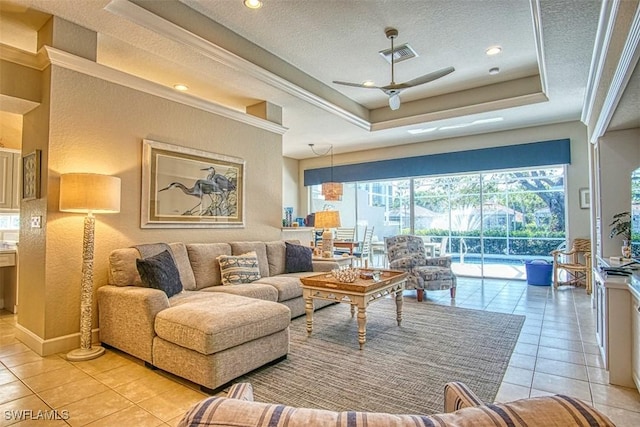 living room with a textured ceiling, light tile patterned flooring, a raised ceiling, and visible vents