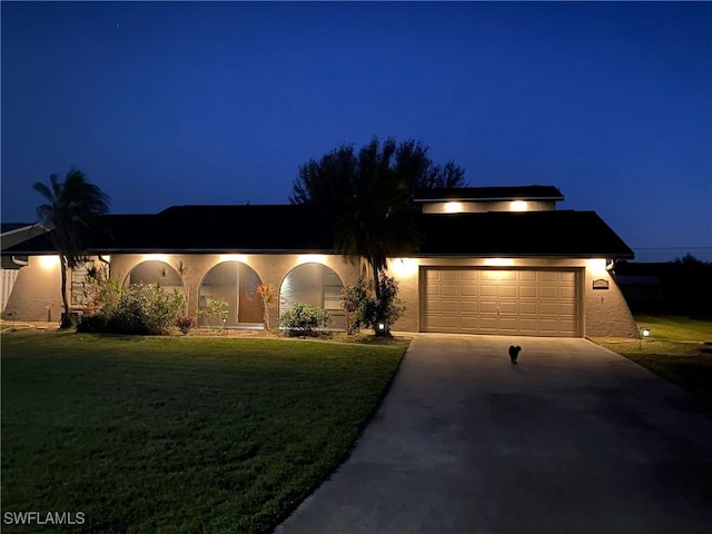 view of front of house with driveway, an attached garage, a lawn, and stucco siding