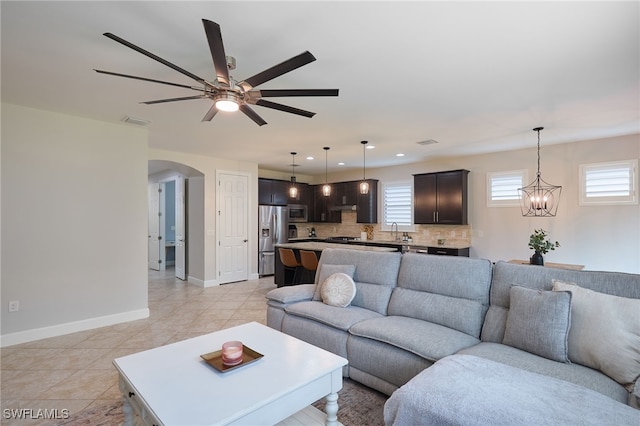 living room with arched walkways, recessed lighting, ceiling fan with notable chandelier, visible vents, and baseboards