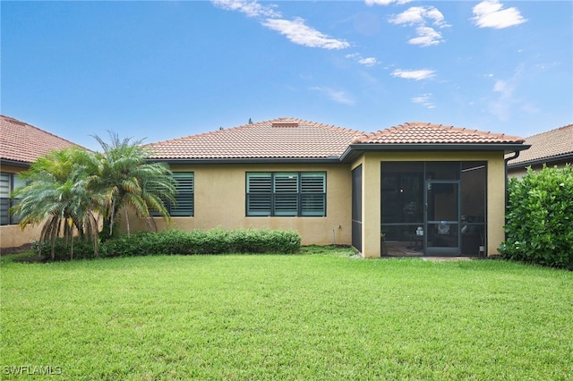 back of house with a sunroom, stucco siding, a lawn, and a tiled roof