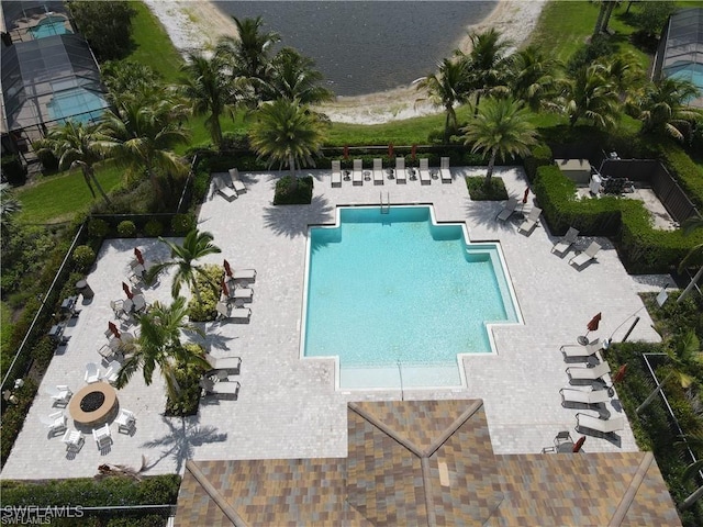 community pool with a patio area, fence, and a water view