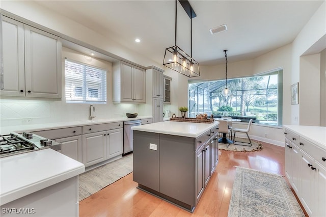 kitchen featuring a center island, stainless steel appliances, light countertops, gray cabinetry, and light wood-type flooring