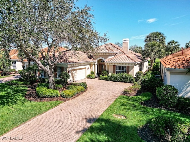 mediterranean / spanish-style house featuring a chimney, a tiled roof, an attached garage, decorative driveway, and stucco siding