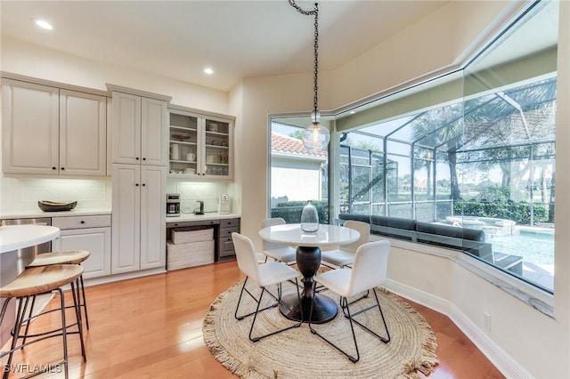 dining area featuring light wood-type flooring, a sunroom, baseboards, and recessed lighting