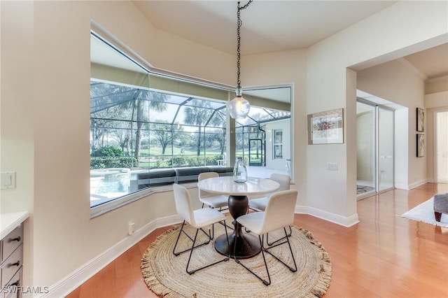 dining area with a sunroom, baseboards, and wood finished floors