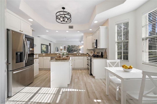 kitchen with a tray ceiling, visible vents, stainless steel appliances, and a wealth of natural light