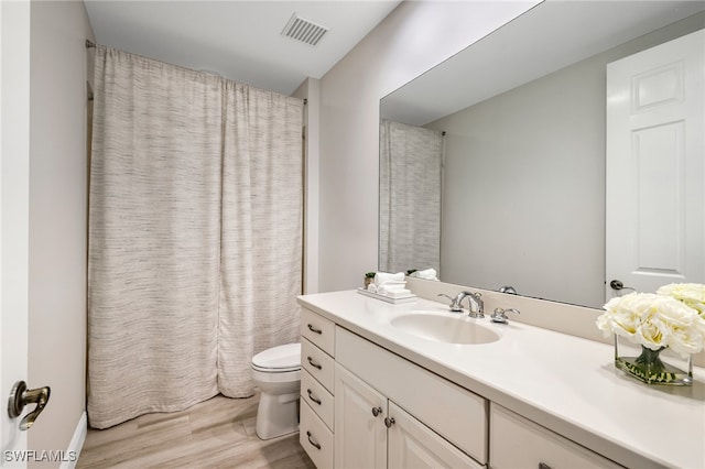full bath with vanity, toilet, a shower with shower curtain, visible vents, and wood finished floors