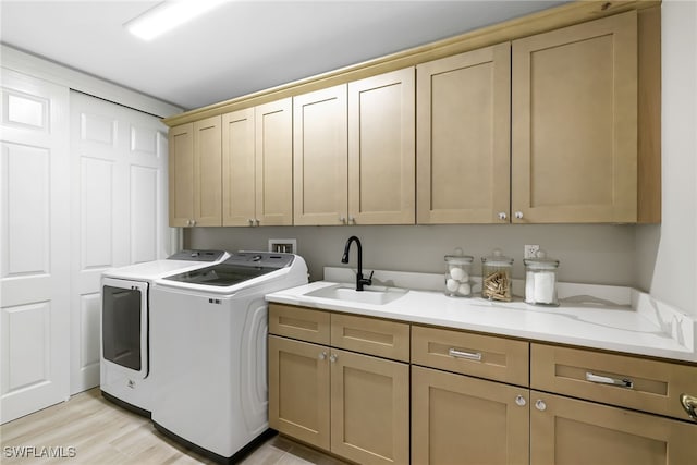 washroom featuring a sink, cabinet space, light wood-style floors, and washer and clothes dryer