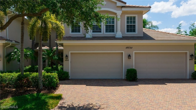 view of front of property featuring a tiled roof, decorative driveway, and stucco siding