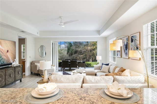 living room featuring visible vents, wood finished floors, and a ceiling fan