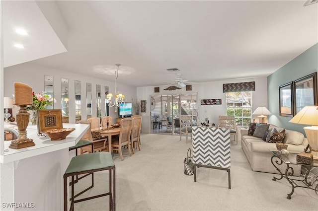 living room featuring visible vents, light carpet, and ceiling fan with notable chandelier