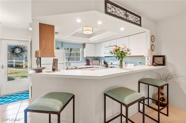 4261 Ute Ct, Estero, FL 33928 - kitchen with a peninsula, white appliances, white cabinets, light countertops, and a raised ceiling