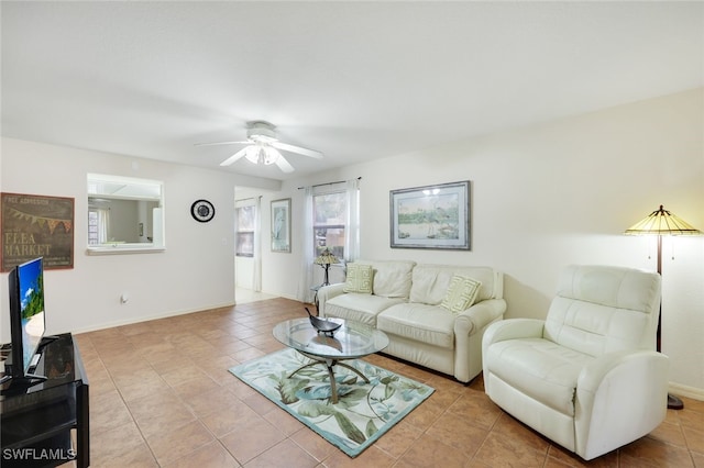 living area with baseboards, a ceiling fan, and tile patterned floors