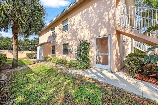 back of property featuring stairs, a yard, and stucco siding