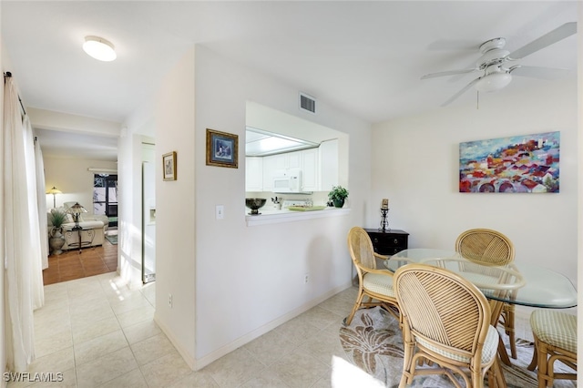 dining room featuring light tile patterned floors, visible vents, baseboards, and a ceiling fan