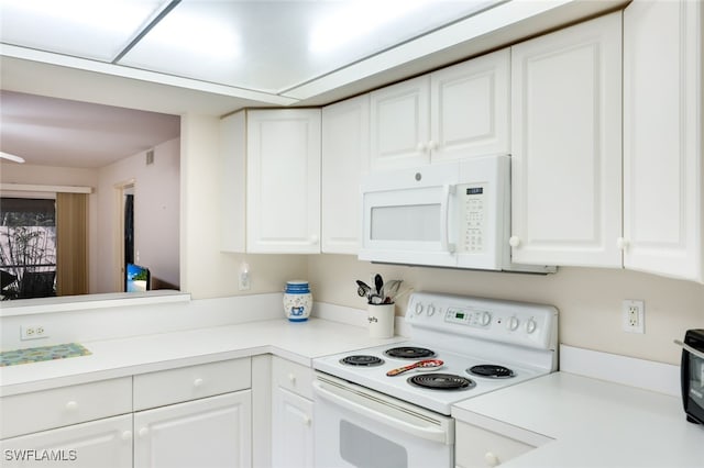 kitchen with white appliances, white cabinetry, and light countertops