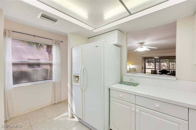 kitchen with white cabinets, white refrigerator with ice dispenser, visible vents, and light countertops