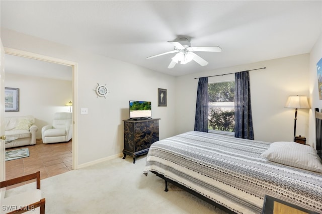 bedroom featuring a ceiling fan, light carpet, baseboards, and light tile patterned floors