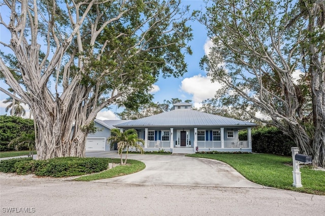 view of front facade featuring covered porch, concrete driveway, metal roof, a garage, and a front lawn