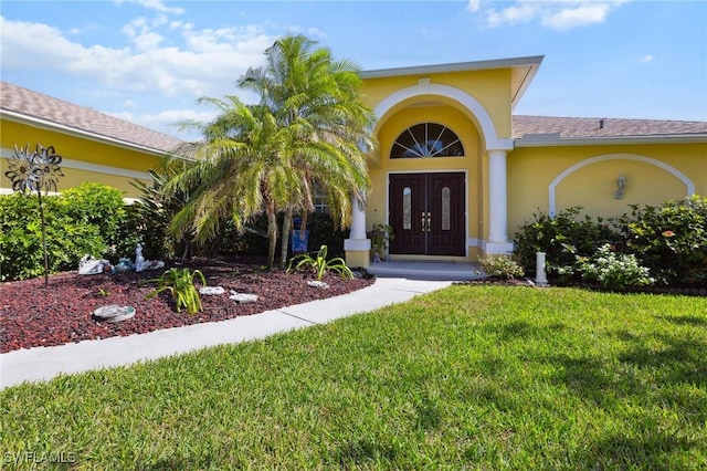 doorway to property with a lawn and stucco siding