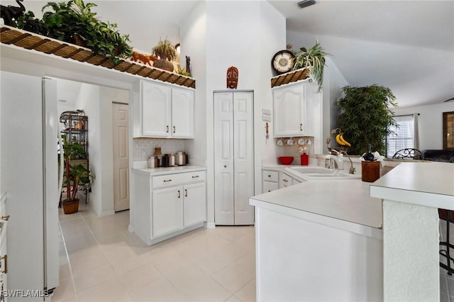 kitchen with light countertops, a sink, freestanding refrigerator, and white cabinetry