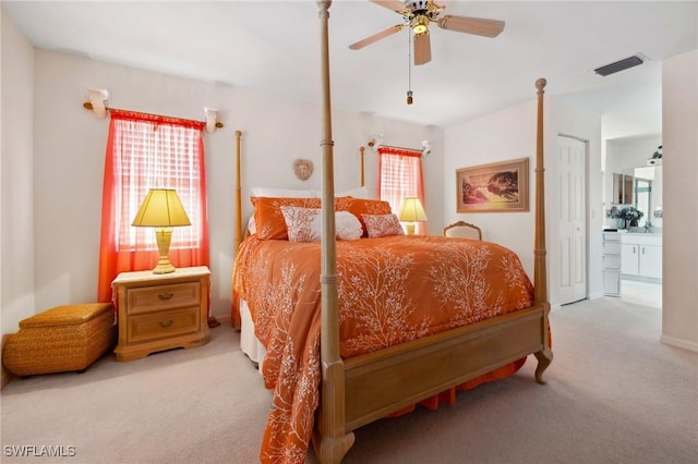 bedroom featuring a ceiling fan, visible vents, connected bathroom, and light colored carpet