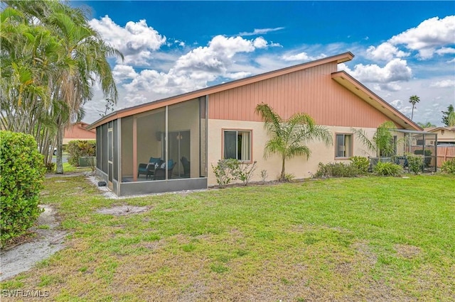 rear view of property featuring a sunroom and a yard