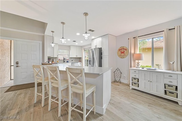 kitchen featuring light countertops, a kitchen island, white cabinets, and stainless steel fridge with ice dispenser