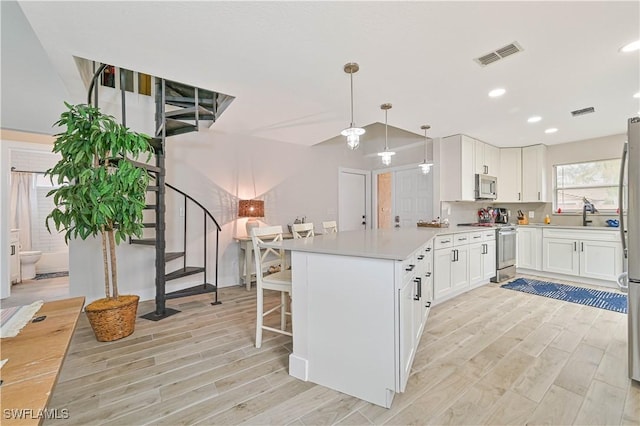 kitchen featuring stainless steel appliances, visible vents, white cabinets, hanging light fixtures, and light countertops