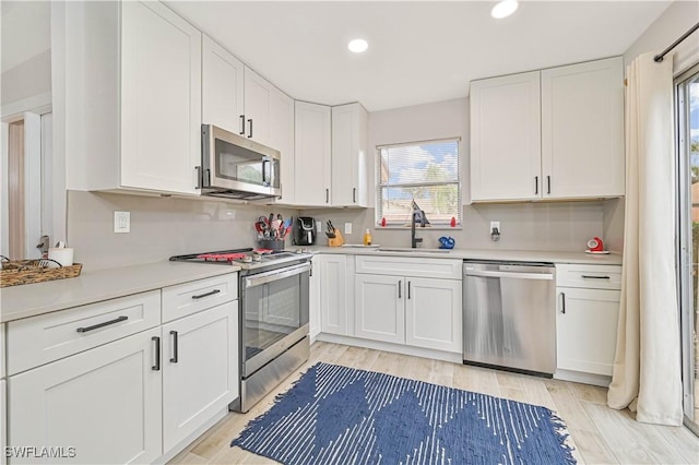 kitchen featuring light countertops, appliances with stainless steel finishes, a sink, and white cabinets