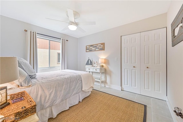 bedroom featuring light tile patterned floors, ceiling fan, baseboards, and a closet