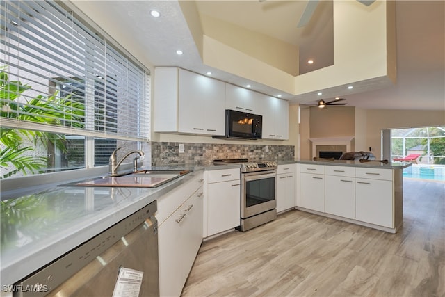 kitchen featuring stainless steel appliances, ceiling fan, sink, white cabinetry, and kitchen peninsula