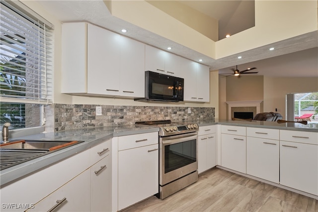 kitchen with stainless steel range with electric stovetop, white cabinetry, backsplash, and light hardwood / wood-style flooring