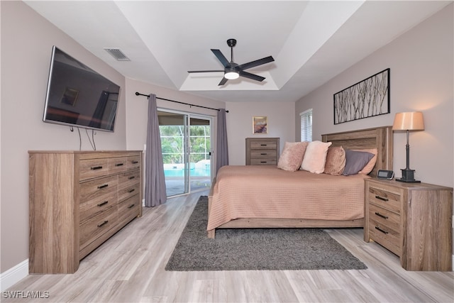 bedroom featuring a tray ceiling, access to outside, light wood-type flooring, and ceiling fan