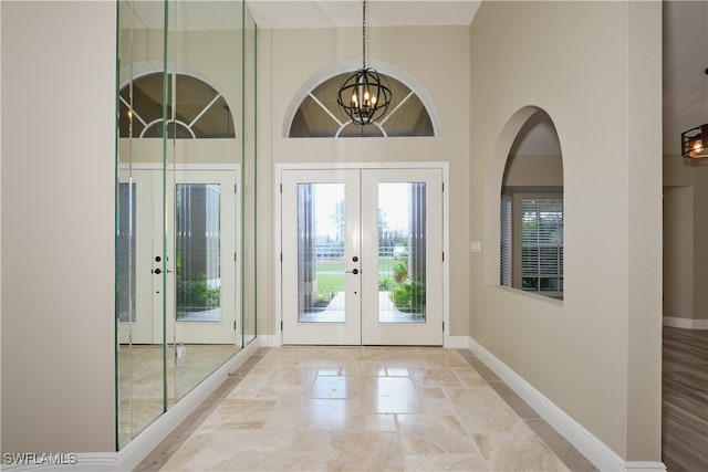 entryway featuring french doors, a towering ceiling, and a notable chandelier