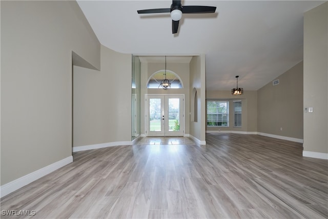 foyer entrance with ceiling fan with notable chandelier, light wood-type flooring, and french doors