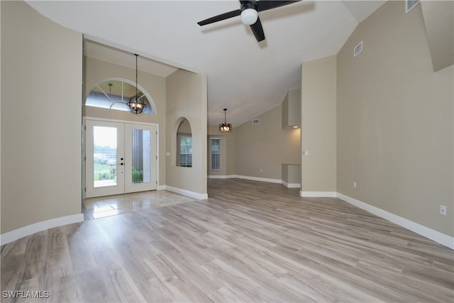 interior space featuring ceiling fan with notable chandelier, light hardwood / wood-style flooring, high vaulted ceiling, and french doors