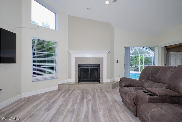 living room with a tile fireplace, high vaulted ceiling, and light hardwood / wood-style flooring