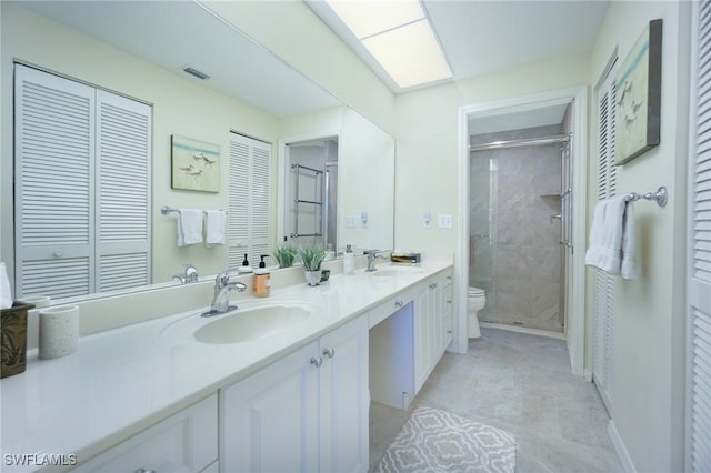 bathroom featuring a shower with shower door, vanity, and toilet