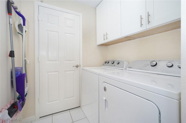 clothes washing area featuring cabinets, washing machine and clothes dryer, and light tile patterned floors