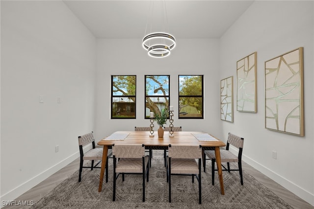 dining space featuring a chandelier, baseboards, and wood finished floors